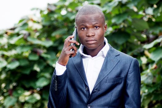 portrait of african businessman standing and communicate with his mobile phone.