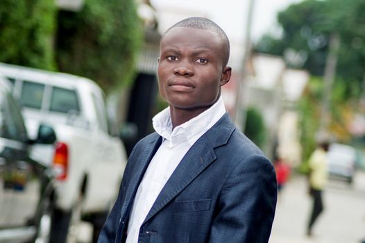 Young man in a suit standing on the street looking at the camera