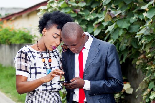 Business people consulting a mobile phone on the street, to see a money transfer.