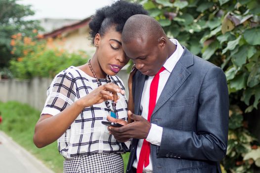 Business people consulting a mobile phone on the street, to see a money transfer.