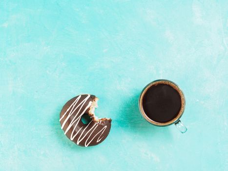 Top view of chocolate donut and coffee on blue concrete background with copy space. Glazed doughnuts and coffee background with copyspace.