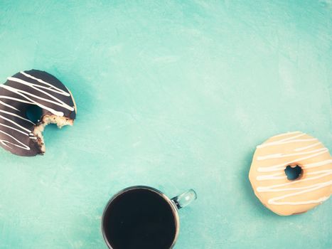 Top view of assorted donuts and coffee on blue concrete background with copy space. Colorful donuts and coffee background. Various glazed doughnuts with sprinkles. Toned image