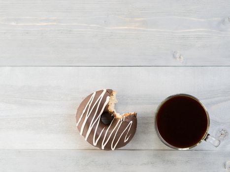 Top view of chocolate donut and coffee on gray wooden background with copy space. Glazed doughnuts and coffee on grey wooden table with copyspace.