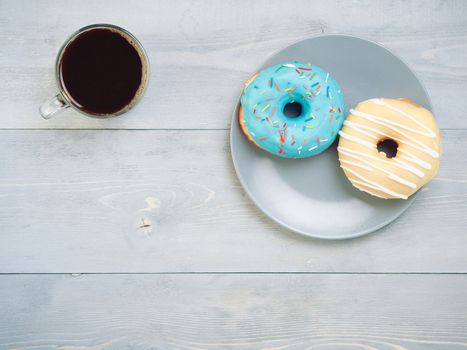 Top view of assorted donuts and coffee on gray wooden background with copy space. Various glazed doughnuts with sprinkles on grey wooden table. Smile sign, good morning concept