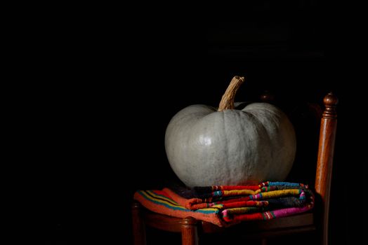raw pumpkin on rustic chair on black background
