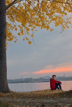 Boy sitting at autumn sunset