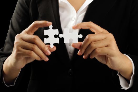 Young businesswoman holding white puzzle isolated on black background, clipping path.