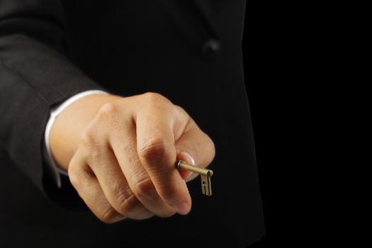 Businesswoman hand holding an antique key isolated on black background, clipping path.    