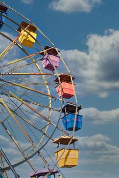 A colorful  ferris wheel at a fair against blue sky