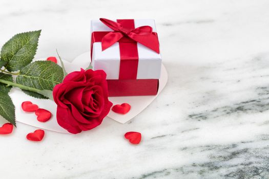 Single red rose with gift box and card on marble stone background in close up layout