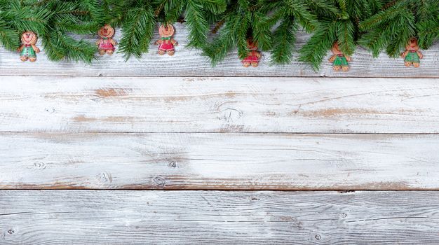 Top border of Christmas evergreen branches and cookie decorations on white vintage wood