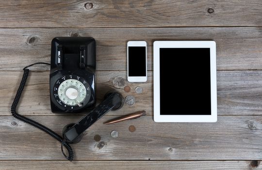 Overhead view of an antique phone with modern wireless devices to replace it 