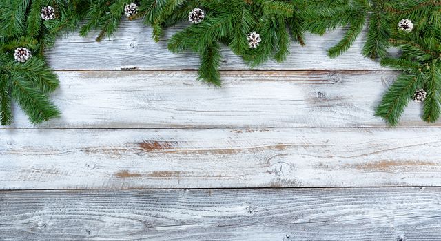 Top border of Christmas tree fir branches and pine cones on rustic wood in flat lay format