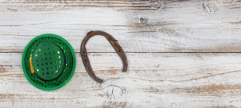 St Patricks day good luck hat and horseshoe on weathered white wood in overhead view