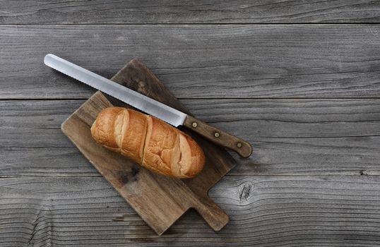 Organic whole wheat loaf with large curated knife on cutting board in top view layout 