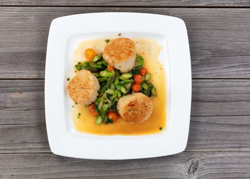 Top view of freshly cooked scallops and vegetables on rustic wooden table 