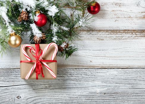 Close up of paper wrapped gift box with decorated Christmas Rough Fir Tree in background  