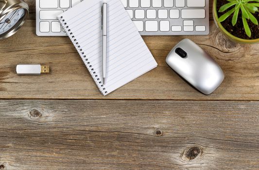 Top part of rustic desktop with work accessories and baby plant. 