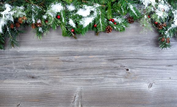 Snow covered Christmas tree evergreen branches placed on top of a rustic wooden background  