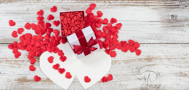 Valentines card and gift box filled with candy heart shapes on rustic white wood in flat lay view