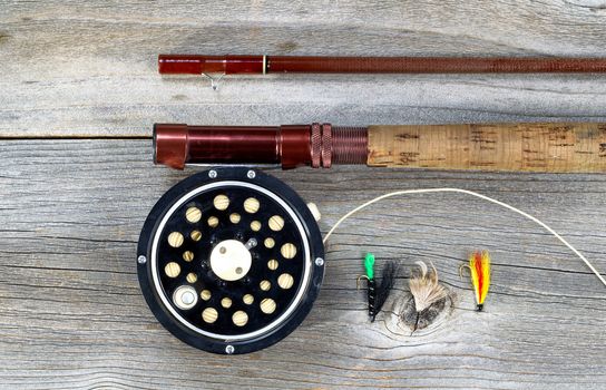 Antique fly fishing reel and rod on rustic wood. Layout in horizontal format.