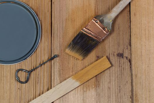 Closeup top view of painting tools consisting of hand brush, stir stick, can opener and paint lid on cedar untreated wooden shingles 