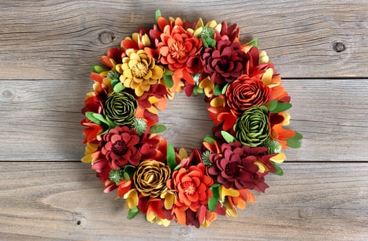 Colorful Wreath made of wooden flowers and leaves on vintage wood background 