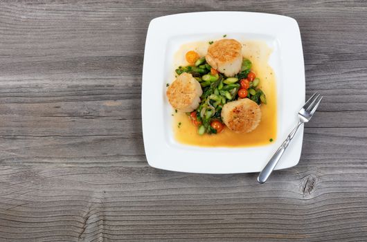 Top view of freshly cooked scallops with vegetables on rustic wooden table 