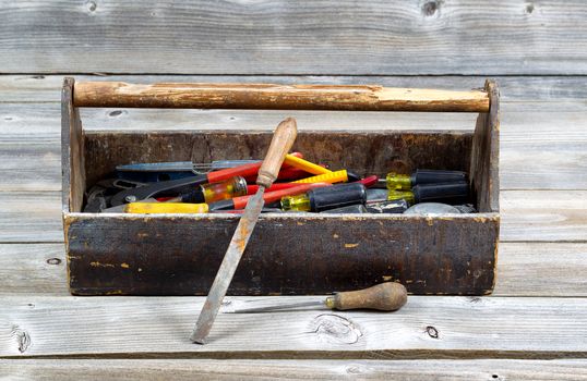 Horizontal image of old tool box filled with tools on rustic wooden boards