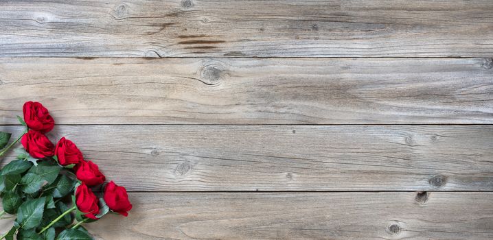 red roses in lower left corner on rustic wood in flat lay view