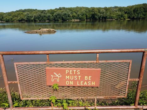 pets must be on leash sign on metal fence with lake or pond