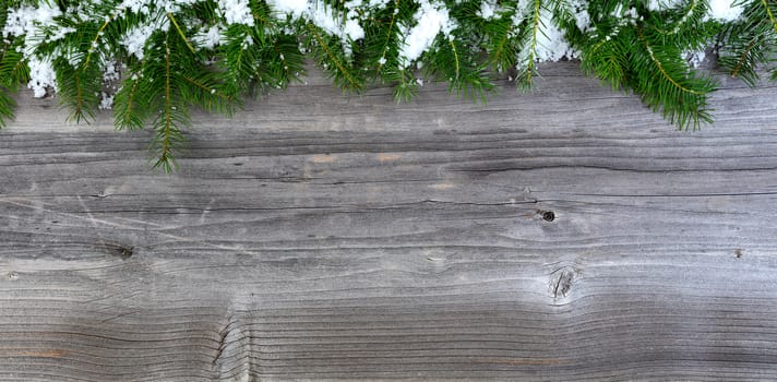 Overhead view of snow covered Christmas fir tree branches on weathered wood for holiday concept 