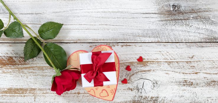 Valentines gift box on top of card with rose and heart shapes in overhead view layout