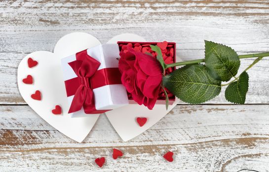 Valentines card with open gift box and single red rose on rustic white wood 