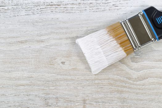 Wet paint brush on old white wooden boards