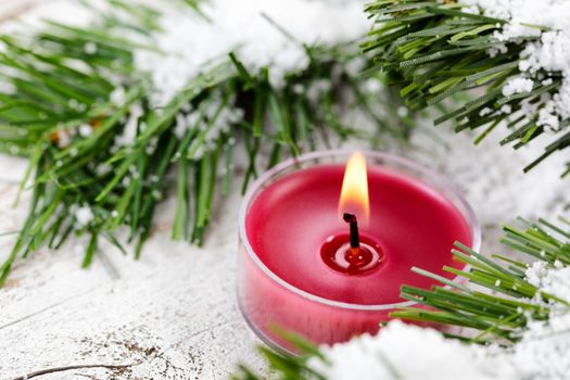 Select focus of glowing candle for Christmas holiday with evergreen and snow 