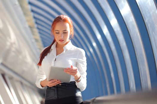 Young Business woman using tablet pc in office corridor against view of an hallway corridor