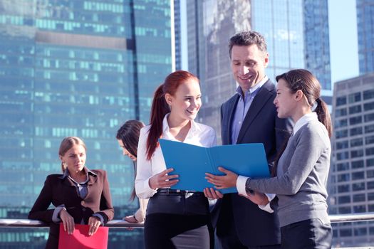 Business people meeting outdoors reding documents over skyscrapers background