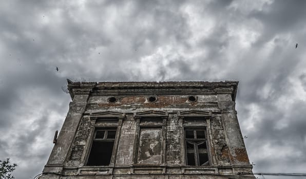 destroyed old building on a gloomy cloudy sky with birds