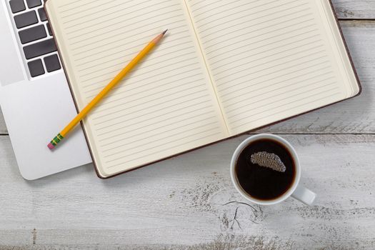 Old white wooden desk with laptop, notepad, pencil and dark coffee. 