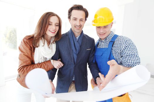 Foreman showing house design construction plan to a happy young couple new house real estate concept