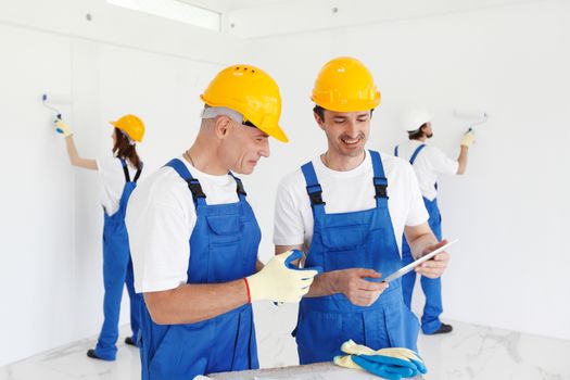 Building, renovation, technology, electricity and people concept - team of builders with tablet pc computer working indoors