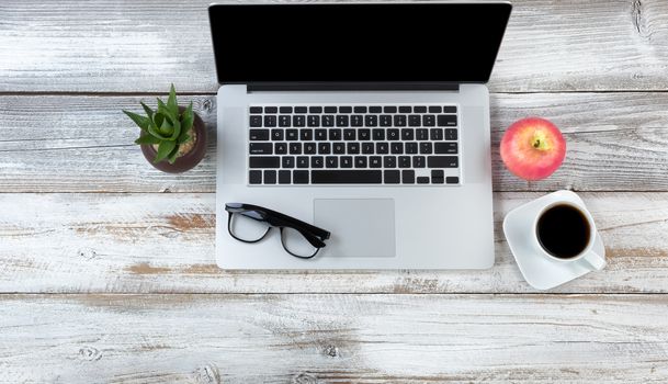 Office desktop setting with laptop plus food and drink on white rustic desk