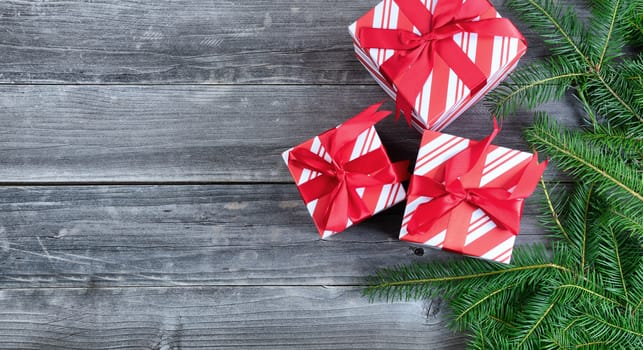 Boxed gifts with Christmas tree branches on weathered wood with copy space available 