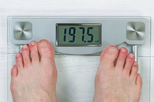 Weight scale, displaying body weight, with bare male feet