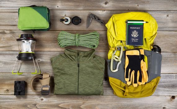 High angled view of organized hiking gear for climbing placed on rustic wooden boards. 