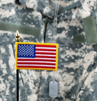 United States of America flag with camouflaged military uniform in background 