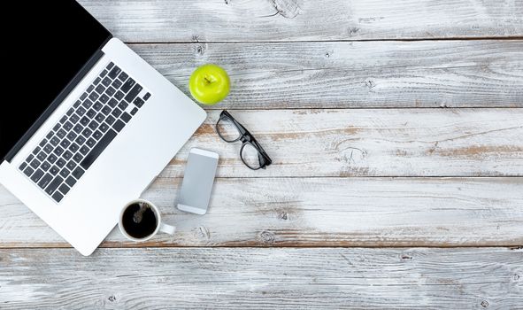 Overhead view of working desktop and smart phone, coffee, reading glasses and green apple with plenty of copy space 