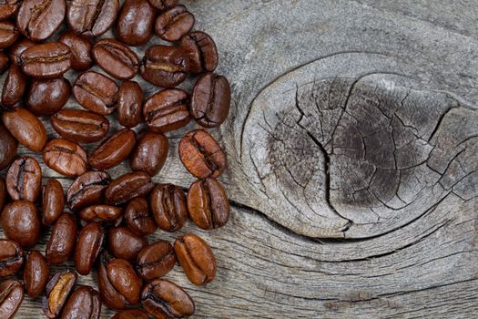 Close up of freshly roasted coffee whole beans on rustic naturally aged wood