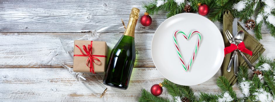 Holiday Christmas and New Year Dinner setting with gifts on rustic table with snow covered branches 